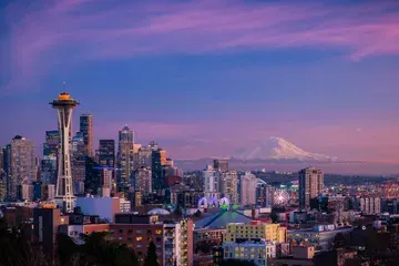 Seattle skyline and Mt Rainier as seen from Kerry Park just after sunset, with a deep blue sky and purple clouds.